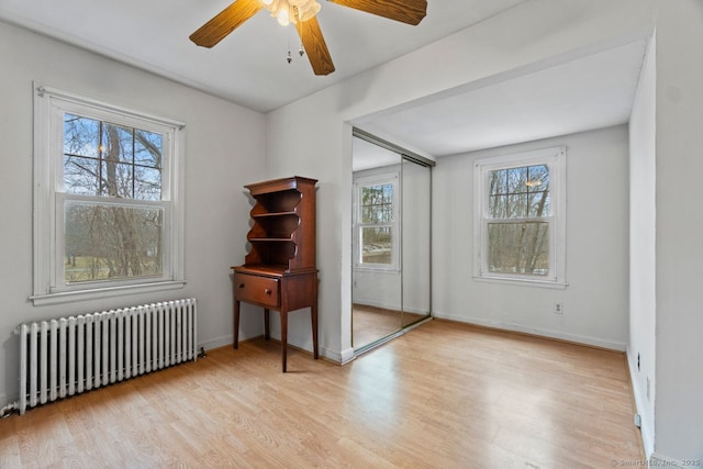 spare room with baseboards, ceiling fan, wood finished floors, and radiator