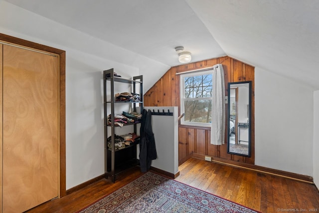 interior space featuring wood-type flooring, baseboards, and vaulted ceiling