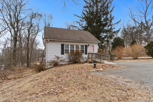 view of front of property featuring driveway and roof with shingles