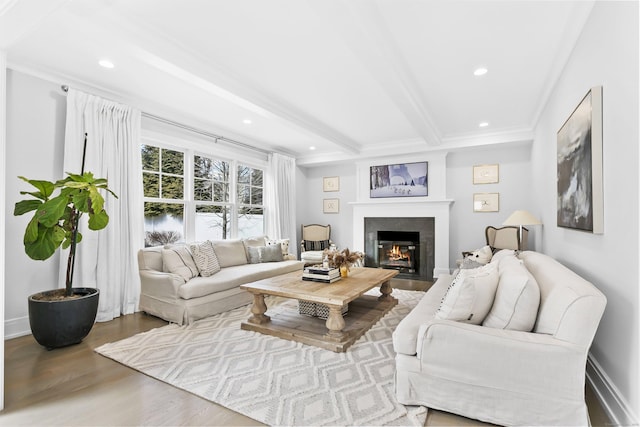 living area featuring recessed lighting, wood finished floors, baseboards, a lit fireplace, and beamed ceiling