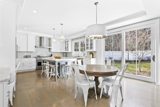 dining area with ornamental molding, wood finished floors, and recessed lighting