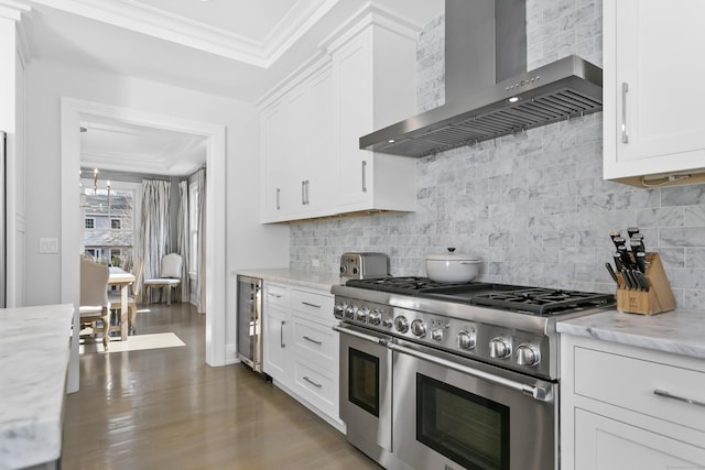 kitchen featuring wood finished floors, white cabinetry, ornamental molding, double oven range, and wall chimney exhaust hood