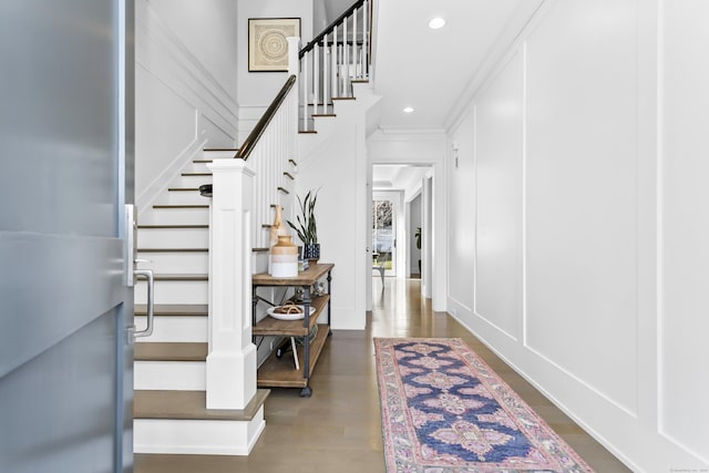 foyer entrance with stairs, a decorative wall, and wood finished floors