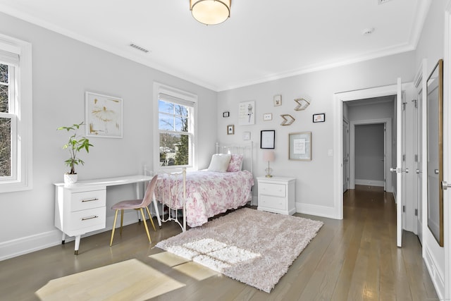 bedroom with baseboards, crown molding, visible vents, and hardwood / wood-style floors