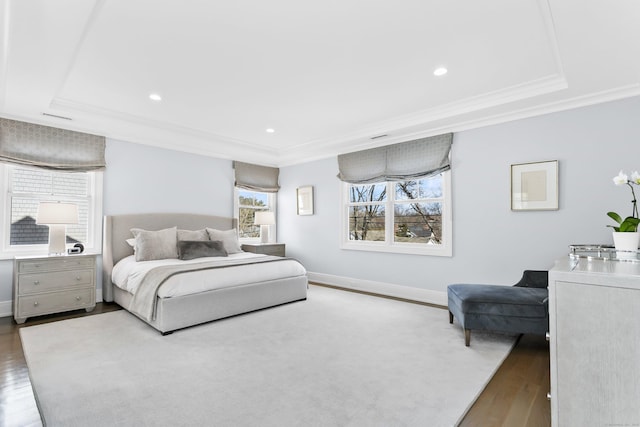 bedroom featuring baseboards, a raised ceiling, wood finished floors, and ornamental molding