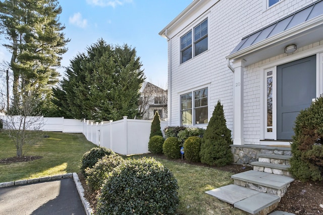 view of home's exterior featuring a yard, a standing seam roof, metal roof, and fence