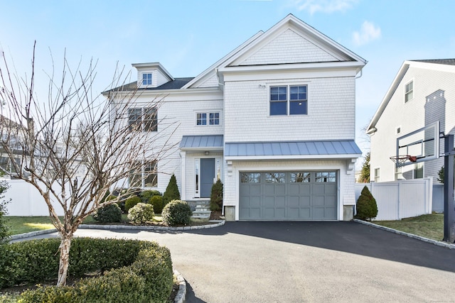 view of front of house with a standing seam roof, metal roof, fence, and aphalt driveway