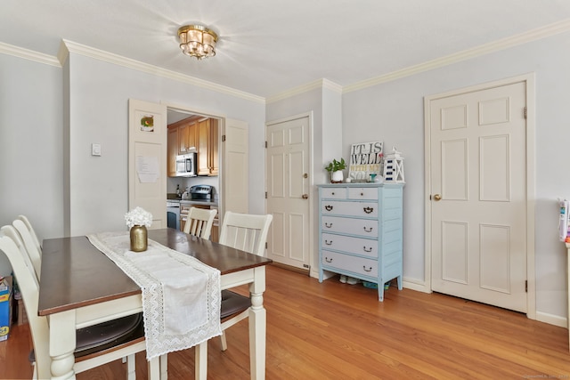 dining area featuring crown molding, baseboards, and light wood-type flooring