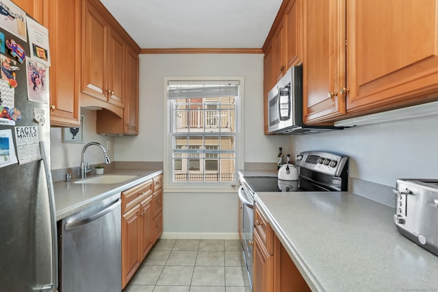 kitchen with crown molding, light countertops, light tile patterned floors, appliances with stainless steel finishes, and a sink