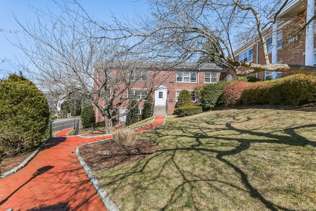 view of front facade with brick siding and a front lawn