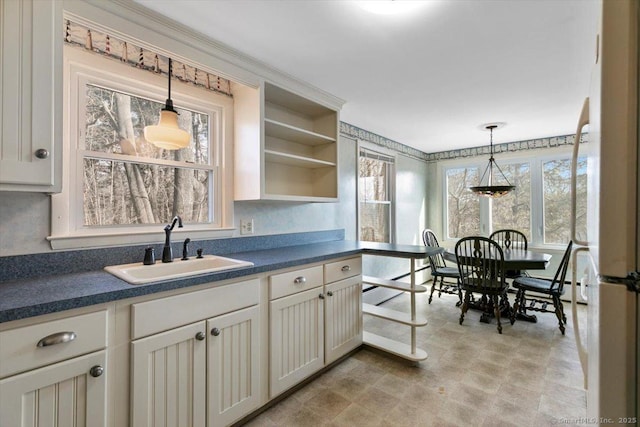 kitchen featuring decorative light fixtures, dark countertops, and a sink