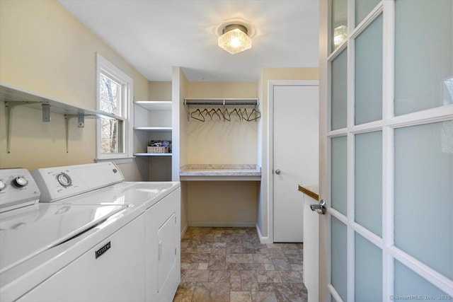 laundry area featuring washing machine and dryer, baseboards, laundry area, and stone finish flooring