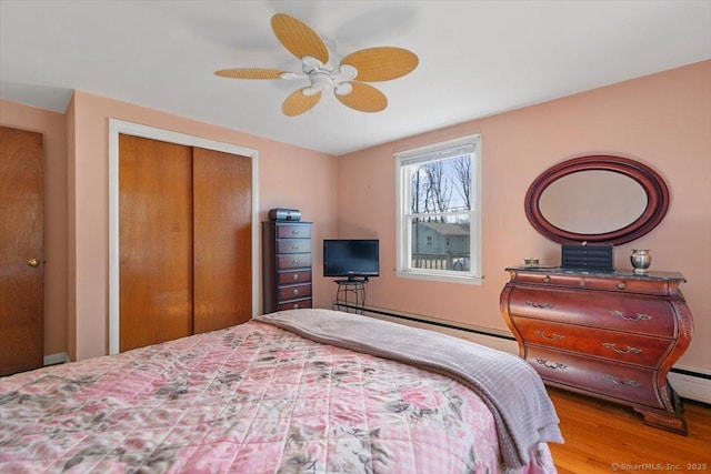 bedroom featuring a baseboard radiator, wood finished floors, ceiling fan, and a closet