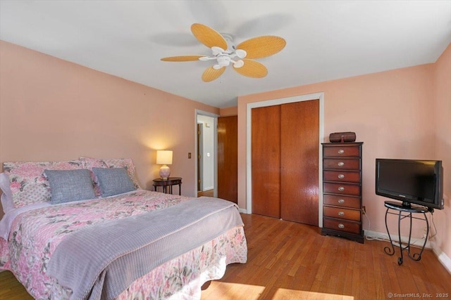 bedroom featuring baseboards, wood finished floors, ceiling fan, and a closet