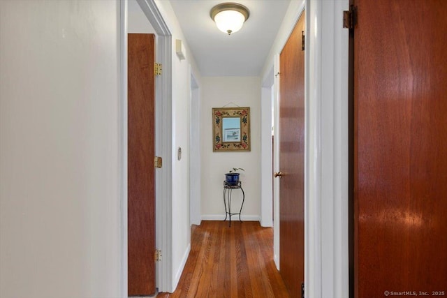hallway featuring wood finished floors and baseboards