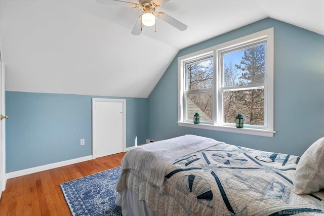 bedroom featuring lofted ceiling, wood finished floors, a ceiling fan, and baseboards