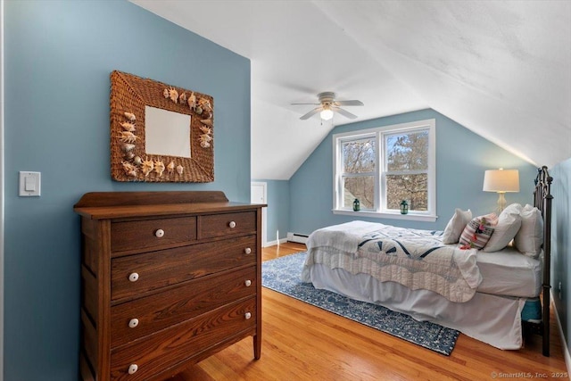 bedroom with vaulted ceiling, a ceiling fan, light wood finished floors, and a baseboard radiator