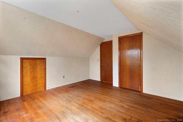 additional living space with wood finished floors and vaulted ceiling
