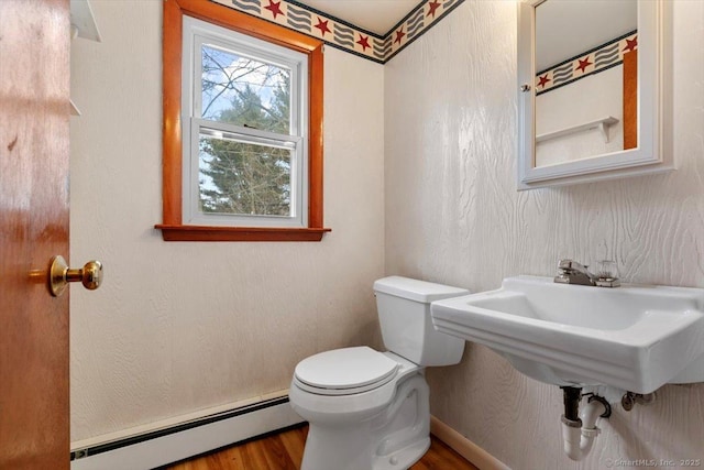 bathroom featuring a baseboard heating unit, toilet, and wood finished floors