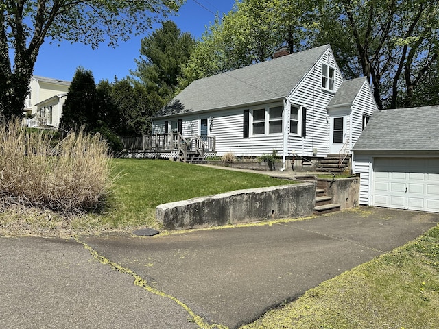 view of front facade featuring a front yard, a chimney, aphalt driveway, roof with shingles, and an attached garage