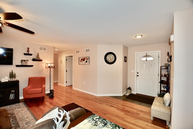 living area with baseboards, visible vents, and wood finished floors