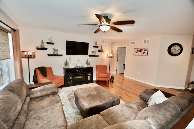 living room featuring a ceiling fan, visible vents, baseboards, and wood finished floors