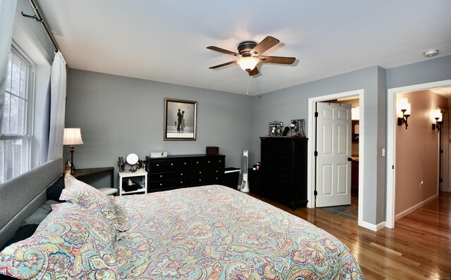 bedroom with a ceiling fan, baseboards, and wood finished floors