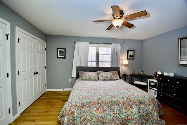 bedroom with multiple closets, ceiling fan, baseboards, and wood finished floors