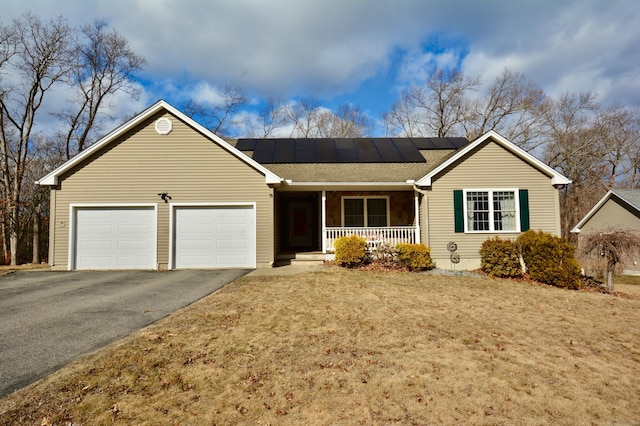 single story home featuring a garage, driveway, a porch, and solar panels