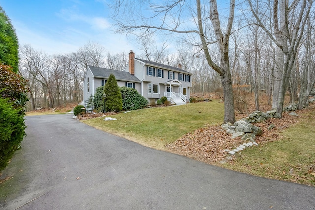 view of front of property featuring aphalt driveway, a front yard, and a chimney