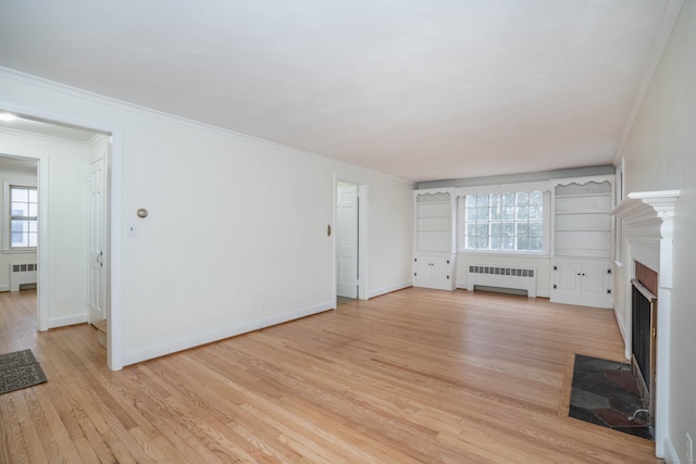 unfurnished living room featuring light wood finished floors, radiator heating unit, a fireplace with flush hearth, and a healthy amount of sunlight