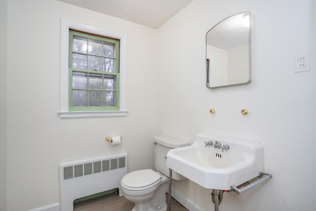 bathroom featuring wood finished floors, radiator heating unit, a sink, and toilet