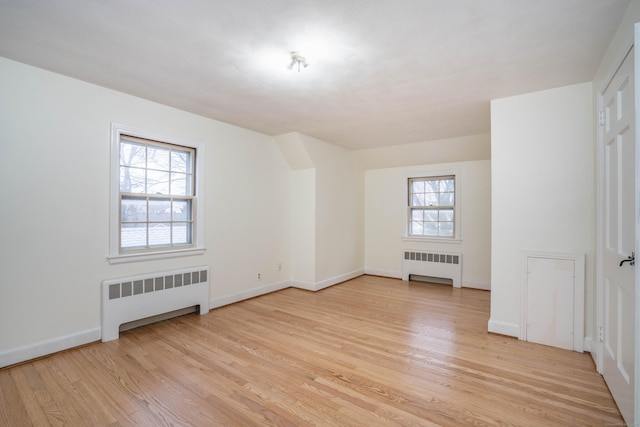 empty room featuring radiator, light wood-style flooring, and baseboards