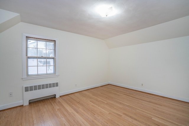 bonus room with radiator, light wood finished floors, baseboards, and lofted ceiling