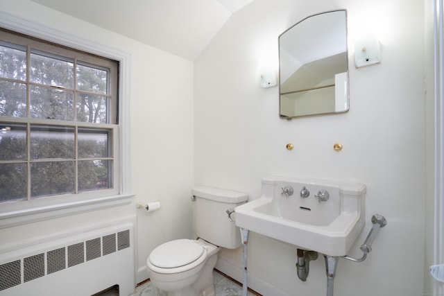 half bathroom featuring radiator heating unit, a sink, toilet, and baseboards