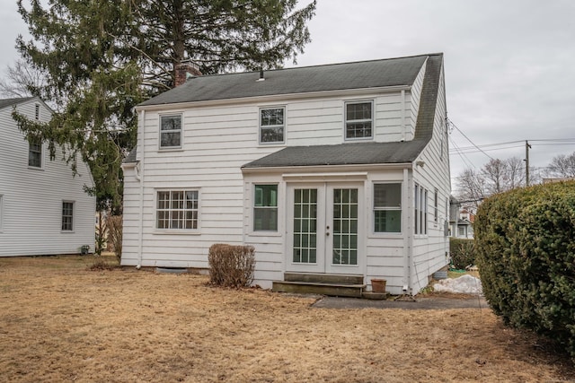 rear view of property with entry steps, a chimney, and french doors