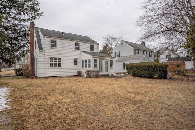 rear view of house featuring a yard, french doors, and a chimney