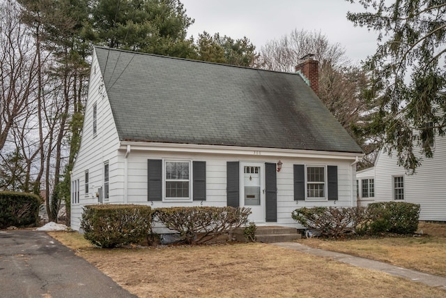 cape cod-style house with a chimney and a front lawn