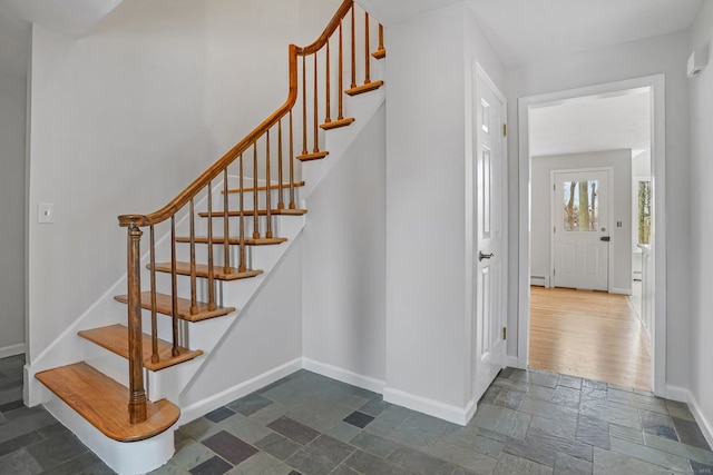 stairway featuring baseboards, baseboard heating, and stone tile floors