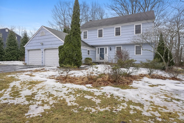 colonial-style house with aphalt driveway and a garage