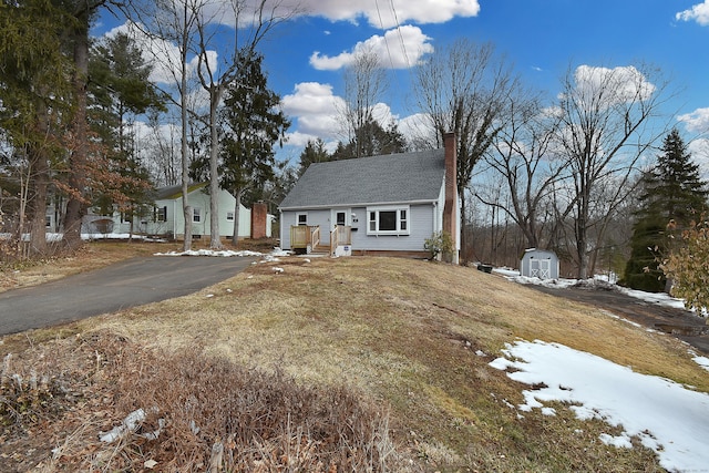 view of front of home featuring a chimney, a storage unit, and an outdoor structure