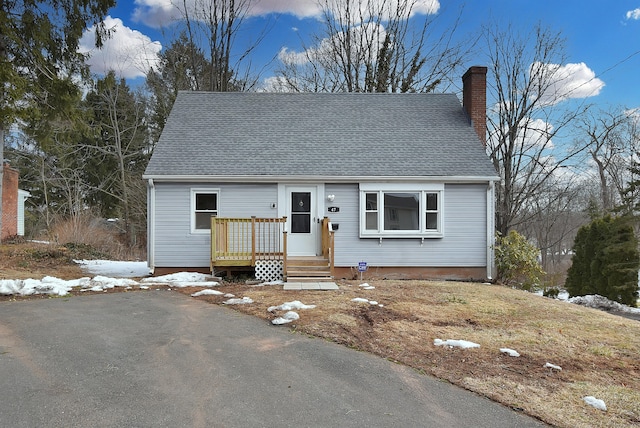 view of front of home featuring a wooden deck, a chimney, and roof with shingles