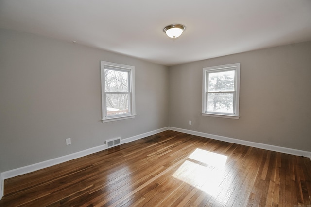 unfurnished room featuring baseboards, plenty of natural light, visible vents, and hardwood / wood-style floors