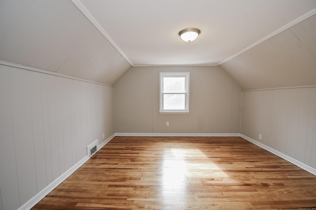 additional living space featuring light wood-type flooring, visible vents, and vaulted ceiling