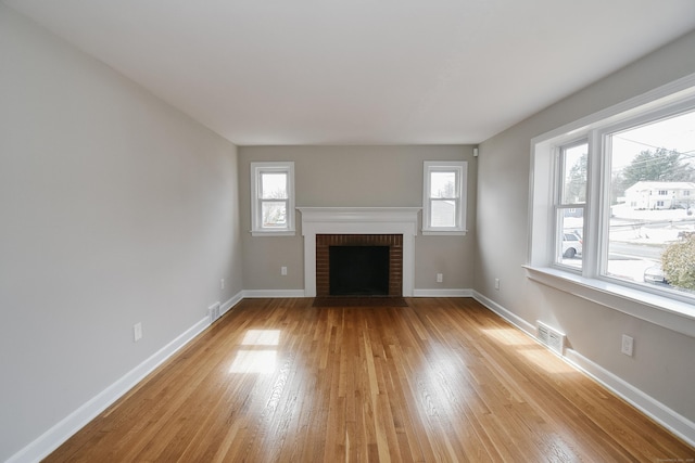 unfurnished living room featuring a wealth of natural light, visible vents, and light wood finished floors