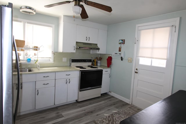 kitchen with electric stove, light countertops, white cabinets, light wood-type flooring, and under cabinet range hood