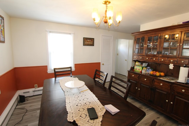 dining room with a chandelier, baseboard heating, and wood finished floors