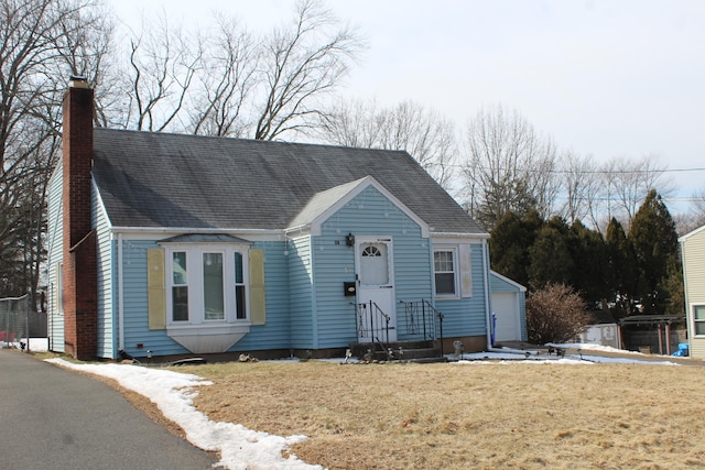 view of front facade featuring a chimney, a front yard, and a detached garage