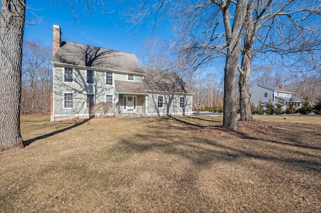 colonial house featuring a chimney and a front lawn