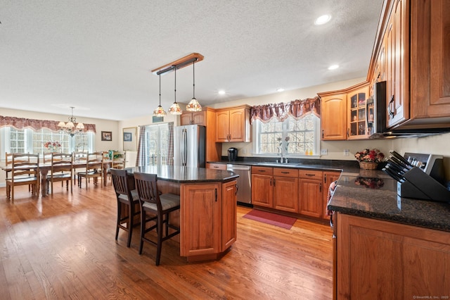 kitchen featuring appliances with stainless steel finishes, light wood-style floors, glass insert cabinets, and a sink